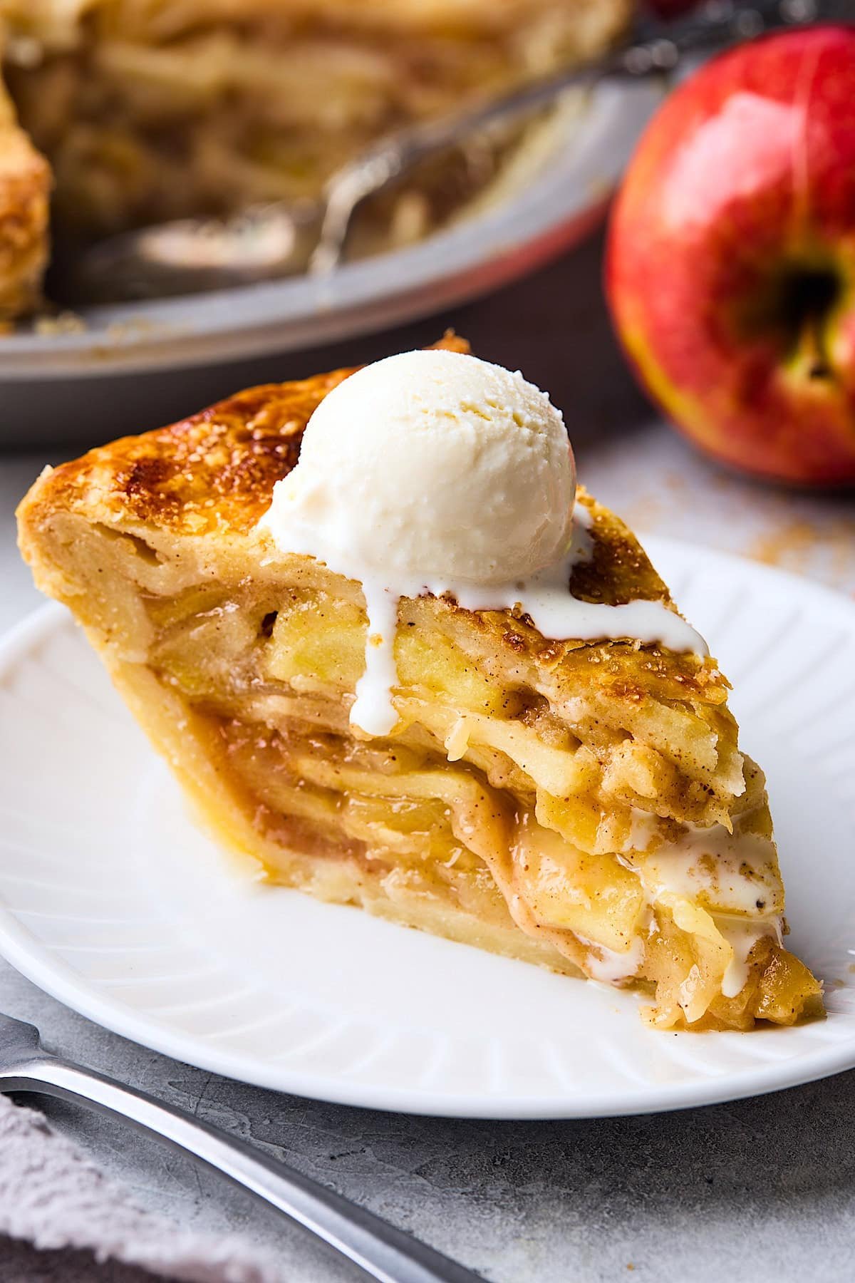 slice of apple pie on plate with scoop of vanilla ice cream.