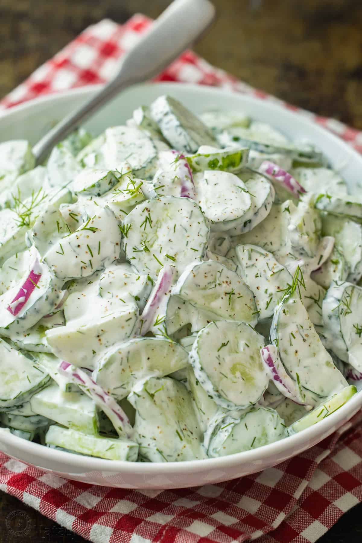 This easy Creamy Cucumber Salad combines cucumbers and red onions with a sour cream, lemon, and dill sauce that won't be able to resist! Creamy cucumber salad recipe in a serving bowl garnished with dill