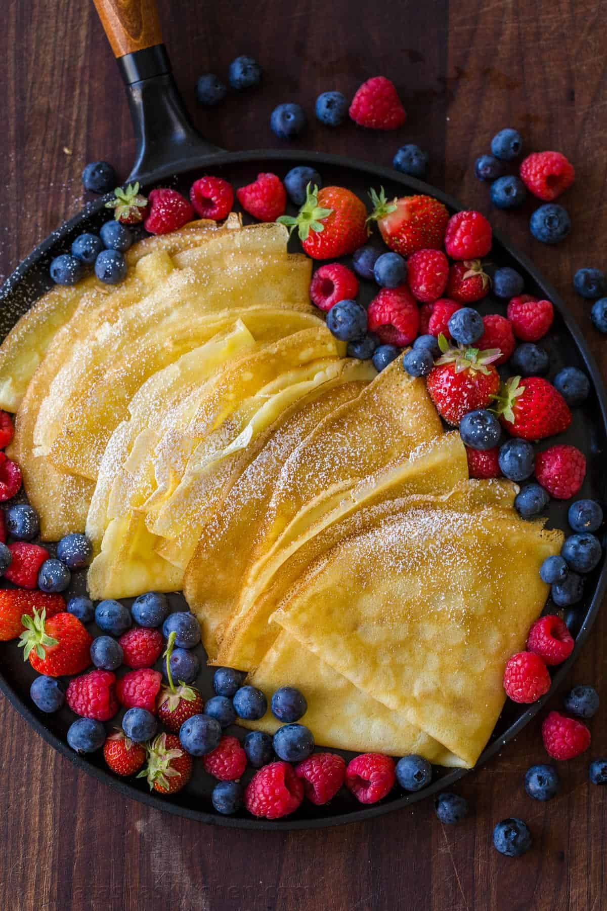 Homemade Crepes stacked in a skillet served with berries