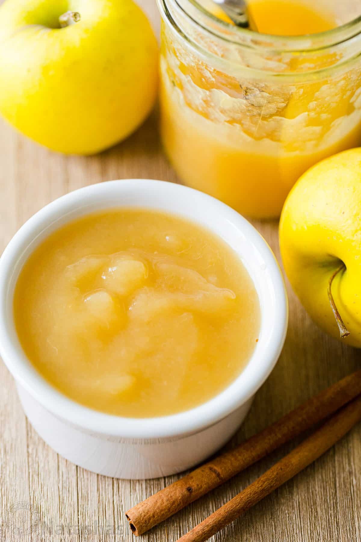 There's nothing like Homemade Applesauce with fresh apple flavor. Use very ripe apples and you don't even need to add sugar. How to make and can applesauce. #applesauce #applesaucerecipe #howtomakeapplesauce #apples #howtocanapplesauce #natashaskitchen #canningrecipes Homemade applesauce in a bowl surrounded by fresh apples and cinnamon sticks