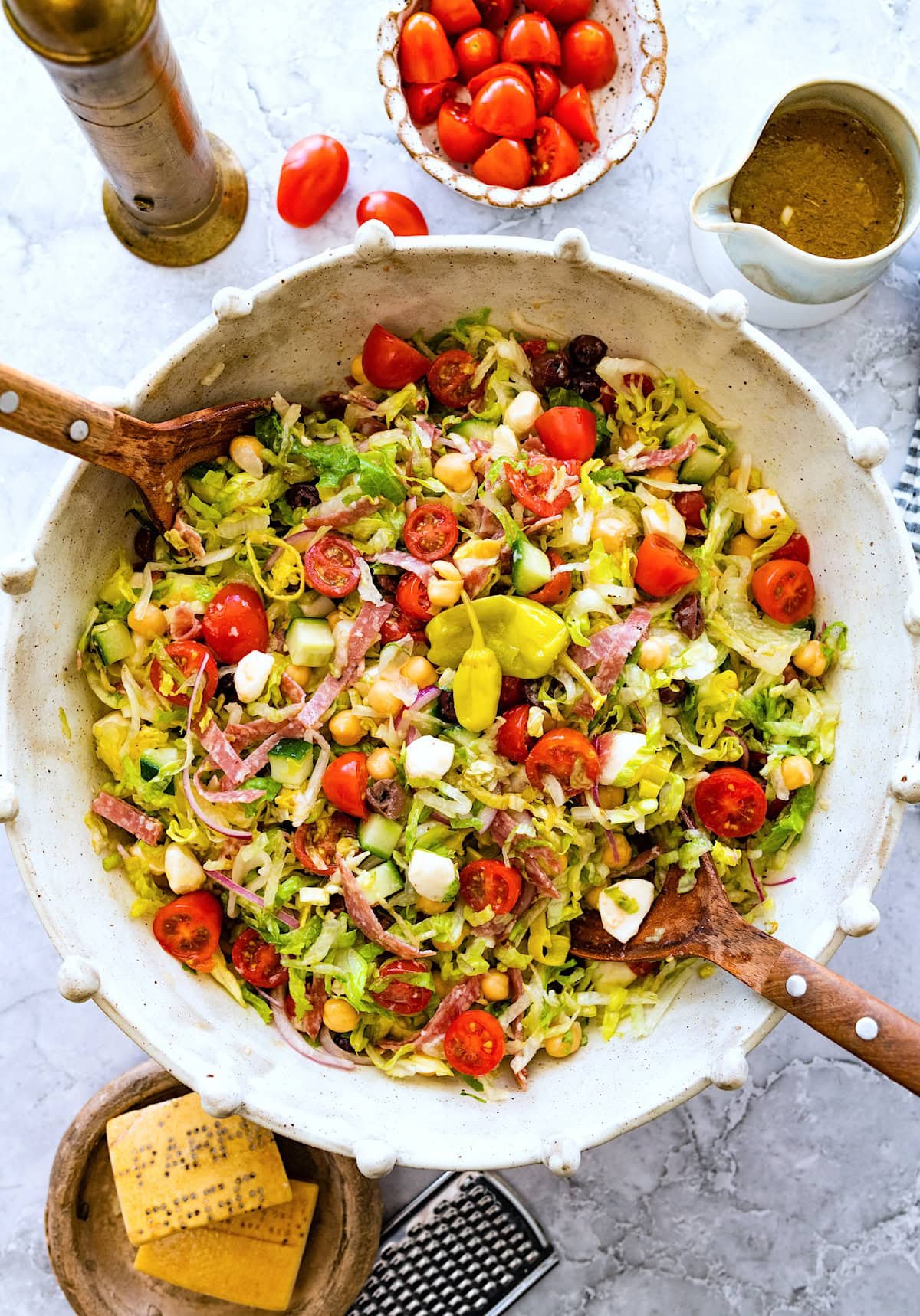 Italian chopped salad in serving bowl with wood salad servers.