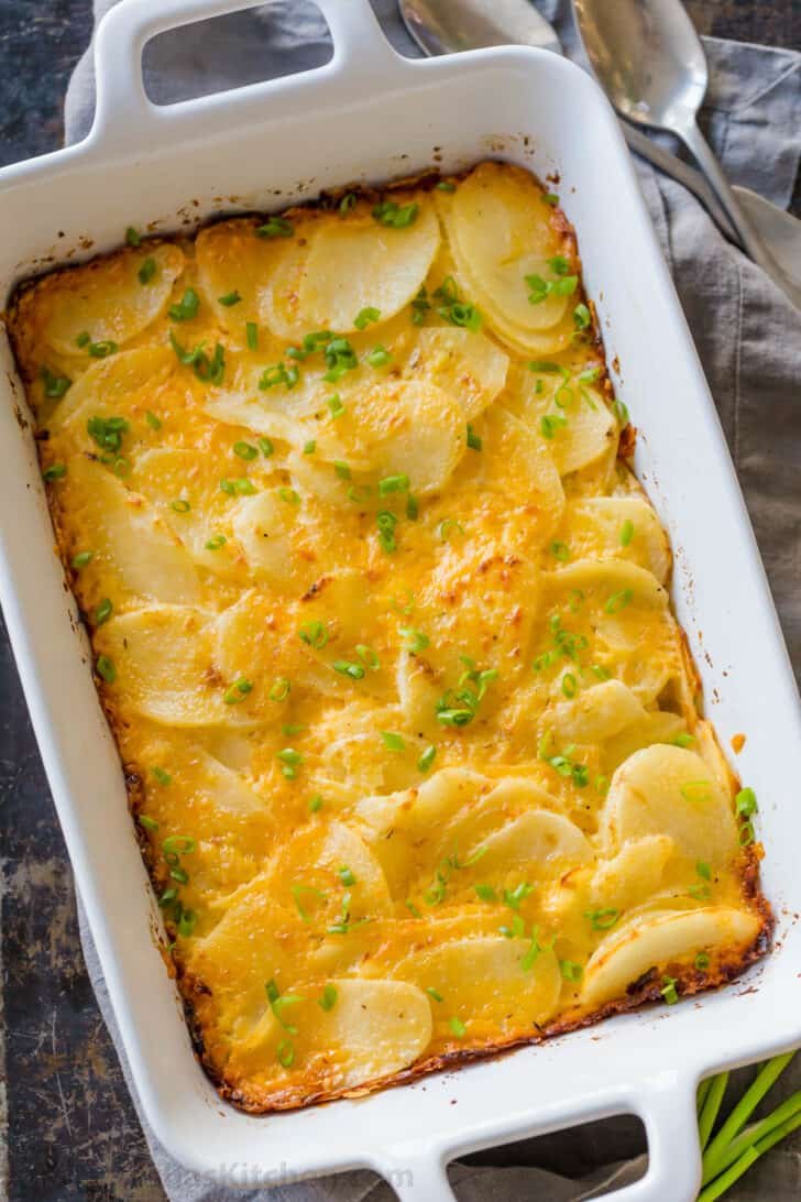 Creamy, cheesy, and easy Scalloped Potatoes Recipe. This holiday-worthy potato side dish has few ingredients and comes together quickly. #scallopedpotatoes #potatocasserole #potatobake Easy scalloped potatoes in casserole dish garnished with chives