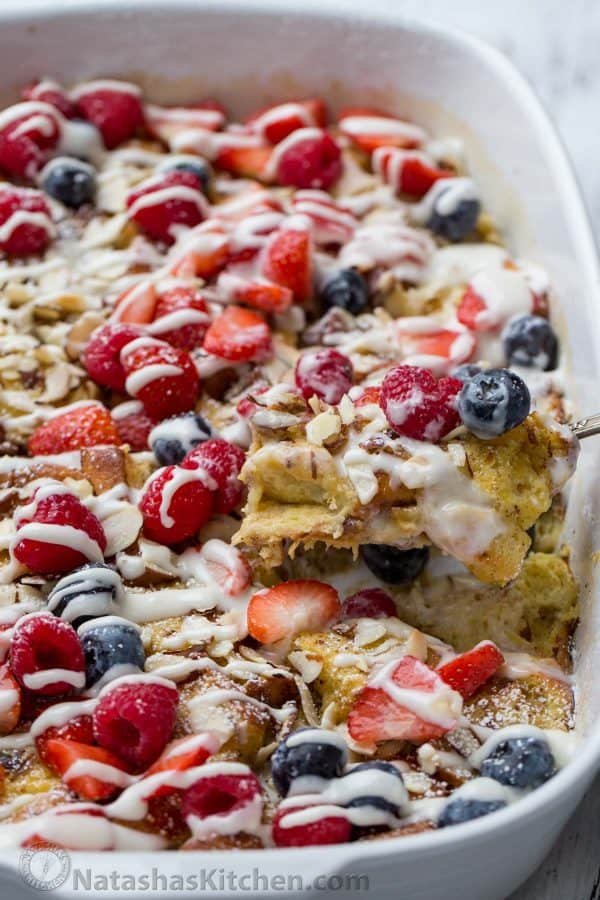 French Toast Casserole in a dish with a spoon, topped with fresh berries. 