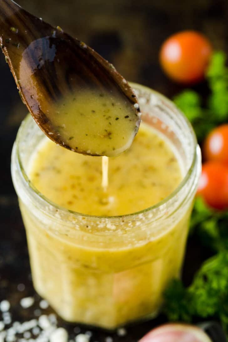 Homemade Italian dressing in a mason jar pouring form a spoon