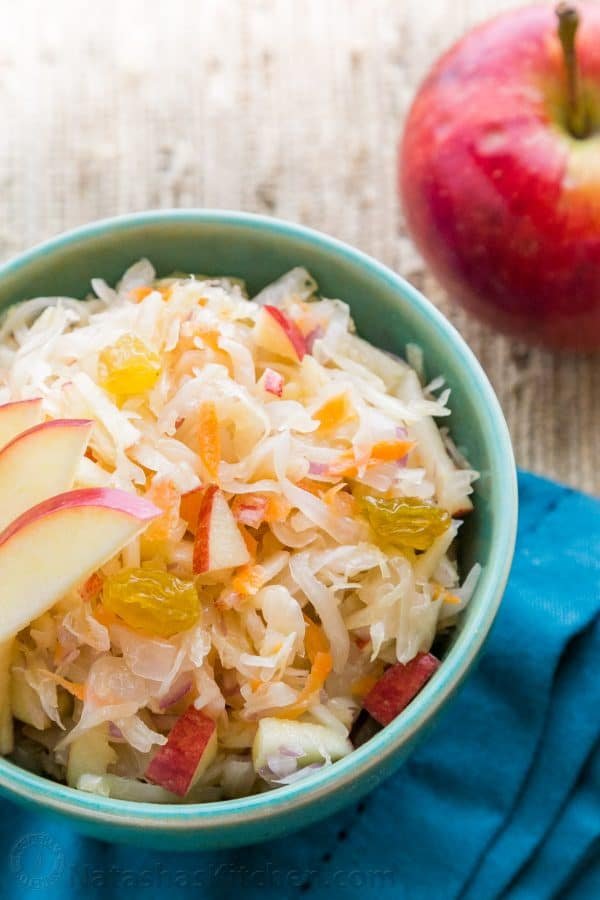 A green bowl of sauerkraut garnished with apples 