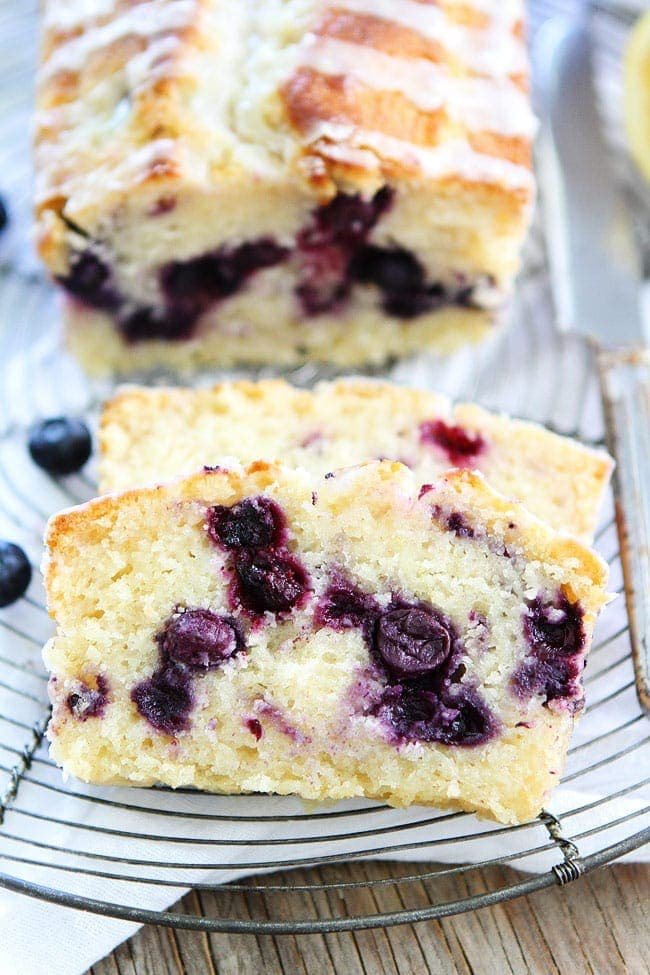 Lemon Blueberry Loaf Cake Recipe on twopeasandtheirpod.com This easy lemon loaf cake is bursting with blueberries is the BEST dessert! You have to try it! Cut Loaf of Lemon Cake with Blueberries inside