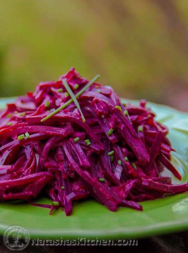 A close up of Mom\'s creamy beet salad on a green plate garnished with chives 