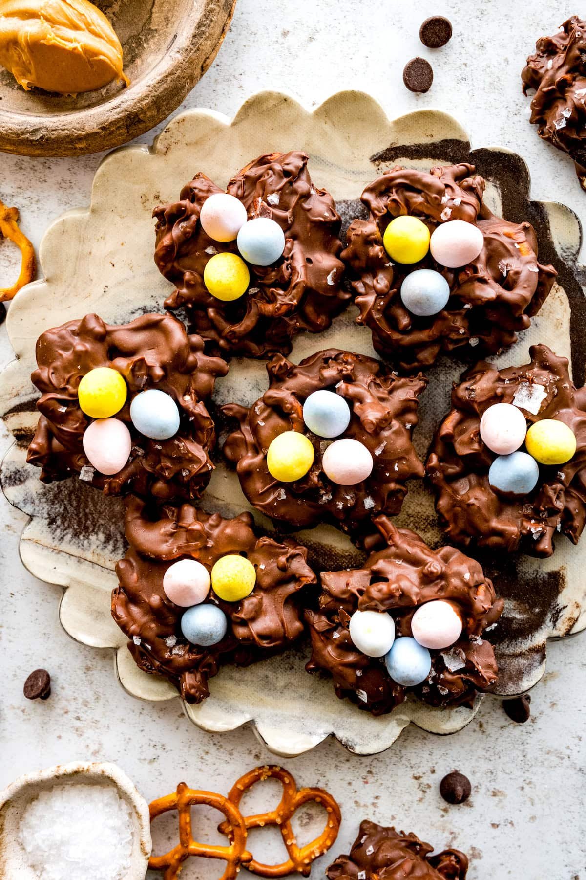 peanut butter pretzel date clusters with cadbury mini eggs on top to look like bird nests on plate.