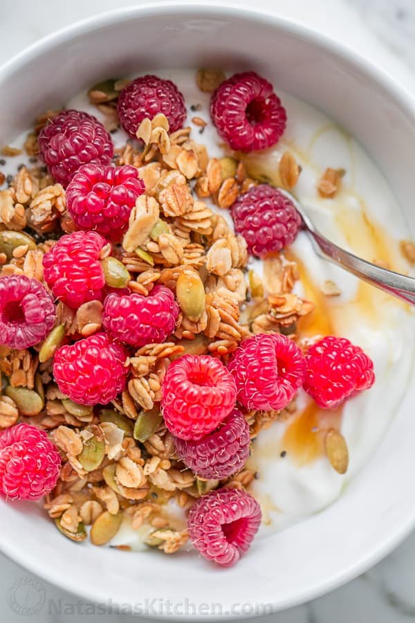 Pumpkin Flax Granola Recipe - crunchy, clustery and sweetened with honey | natashaskitchen.com Homemade granola recipe served over yogurt and topped with fresh raspberries and honey