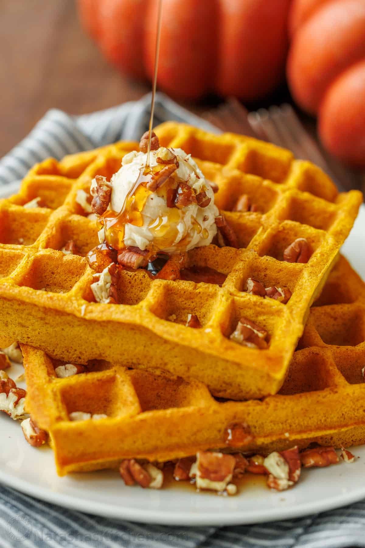 Pumpkin waffles on a plate, topped with butter and syrup, ready to eat