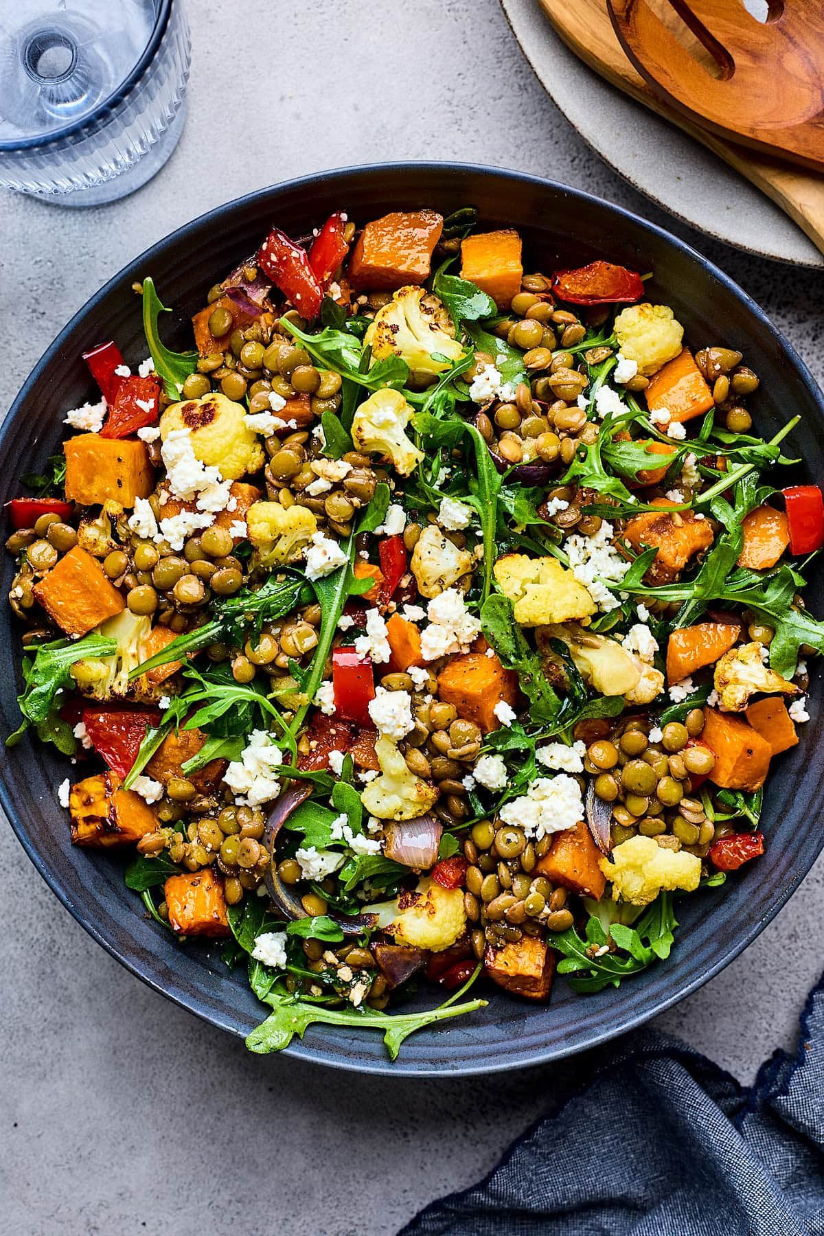 roasted vegetable lentil salad with arugula and feta cheese in bowl.