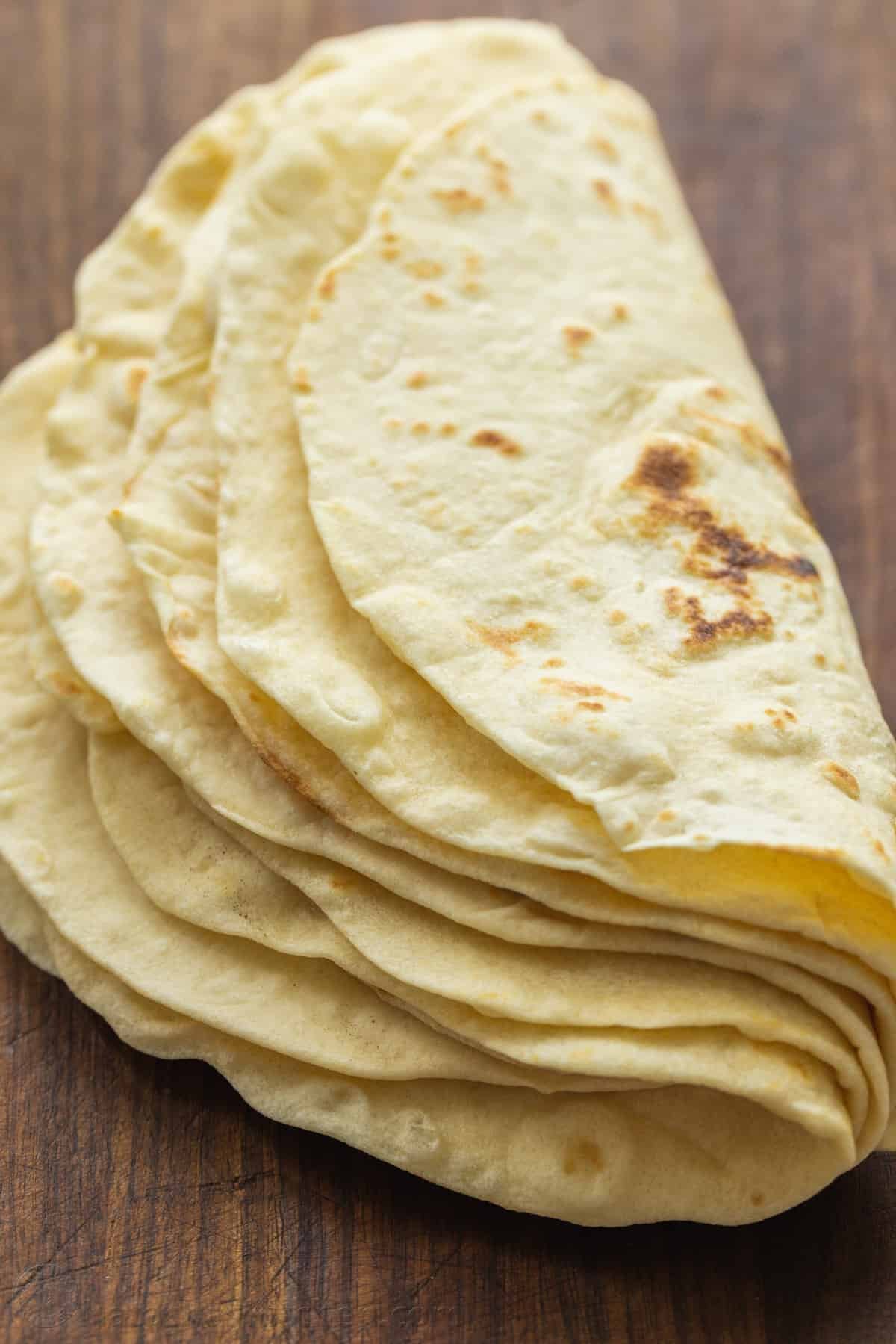 A stack of homemade flour tortillas folded in half.