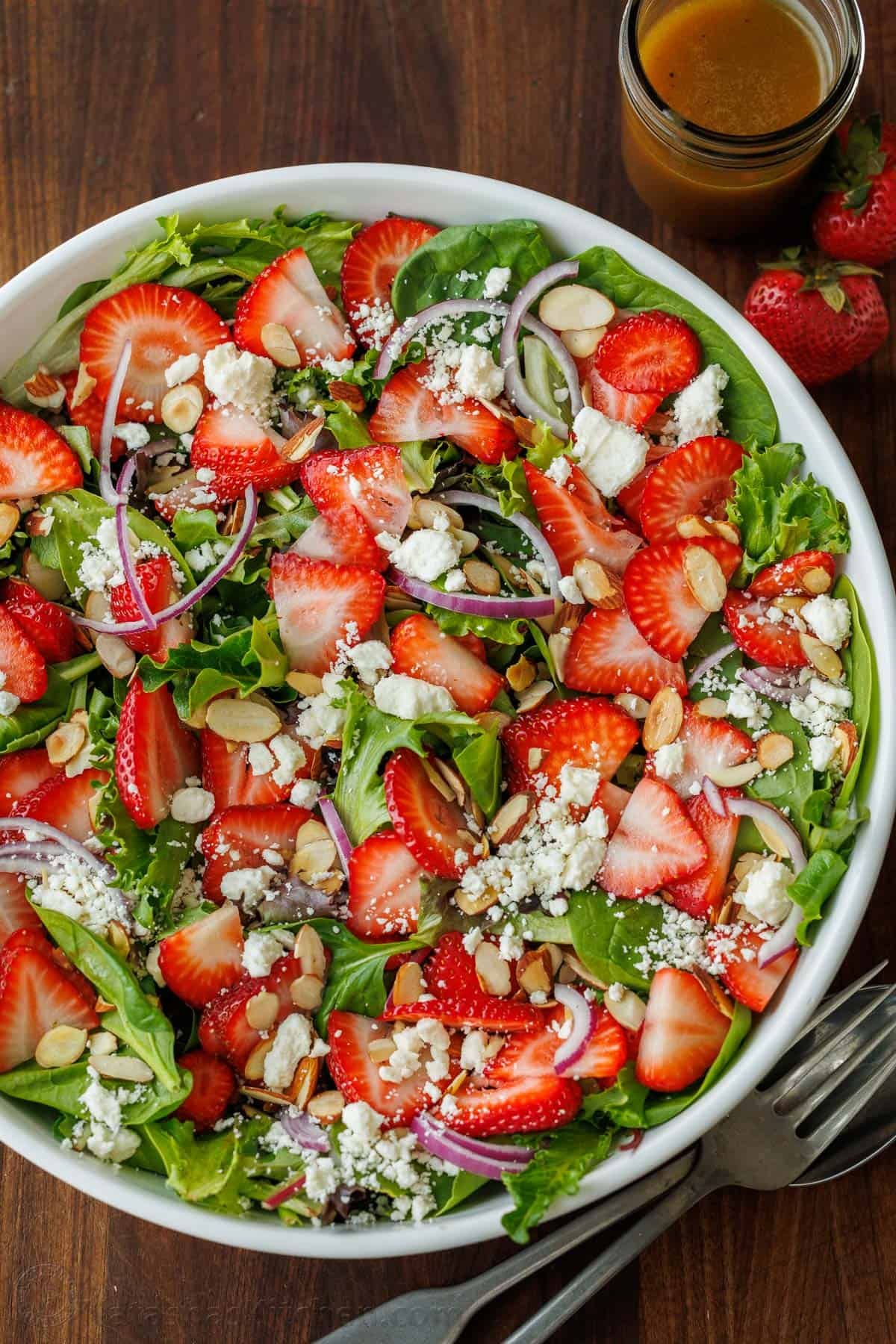 Our summer Strawberry Salad with Honey Vinaigrette is both beautiful and delicious with toasted almonds and feta. Serve in just 10 minutes! strawberry salad with honey vinaigrette in a white bowl