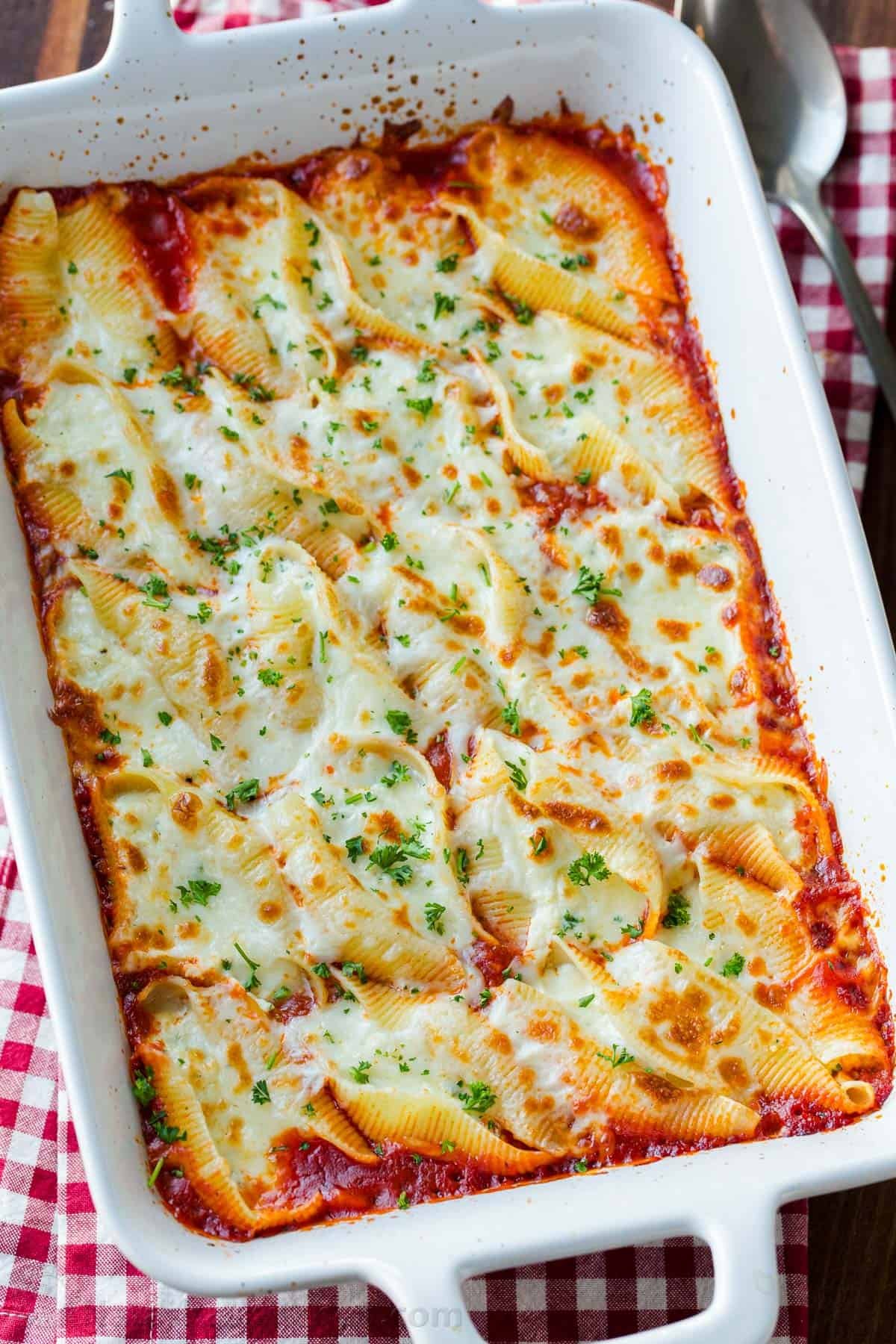Stuffed Shells filled with ricotta, parmesan, and melty mozzarella cheese. Stuffed Pasta Shells always disappear fast and reheat well. Stuffed pasta shells in casserole garnished with parsley