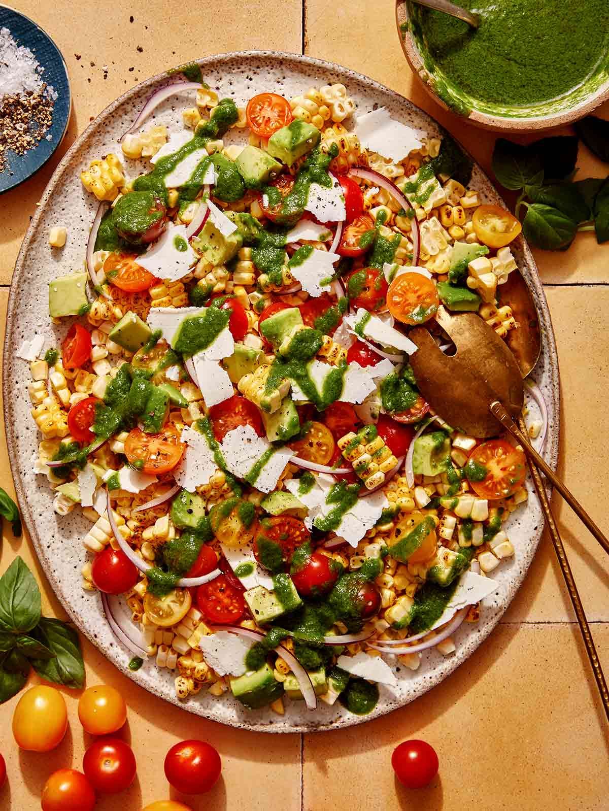 Corn salad on a platter with basil vinaigrette on the side. 