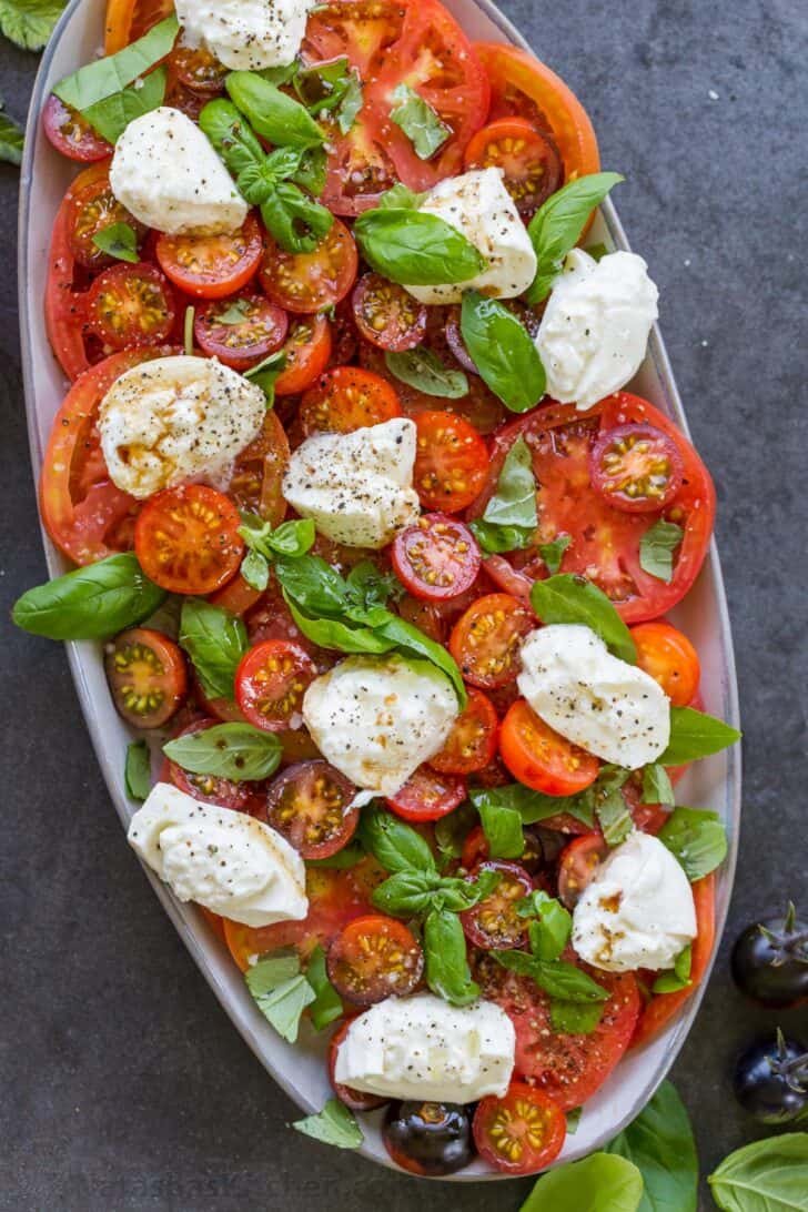Tomato Burrata Salad is one of the easiest Summer salads. The rich burrata cheese is delicious with tomatoes, basil, olive oil, and balsamic. Tomato Burrata salad on a plate
