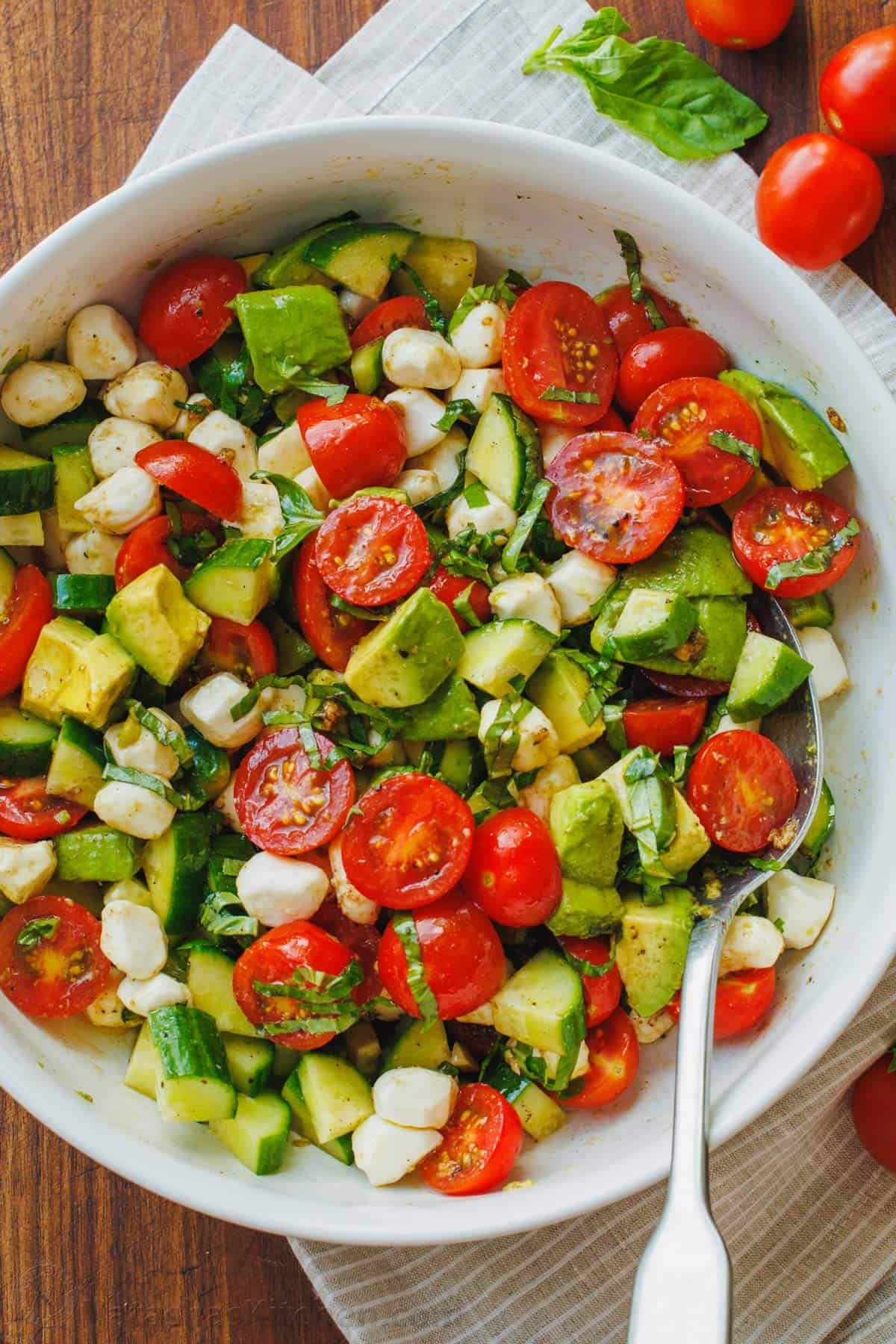tomato cucumber mozzarella salad in a bowl with a spoon