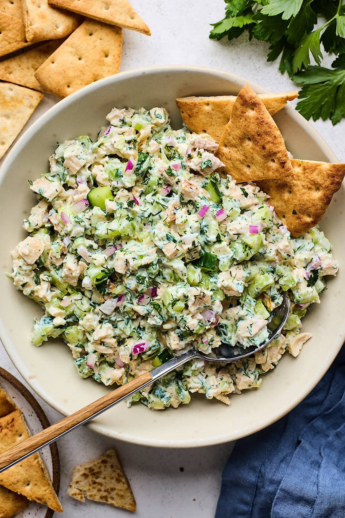 Tzatziki chicken salad in bowl with pita chips and spoon.