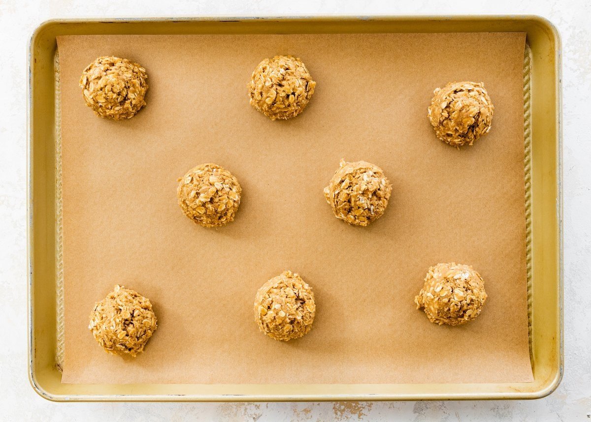 oatmeal cookie dough balls on baking sheet lined with parchment paper.