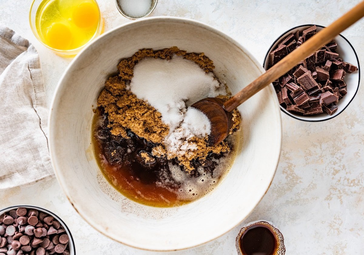 brown butter and sugars being mixed in bowl with wooden spoon. 