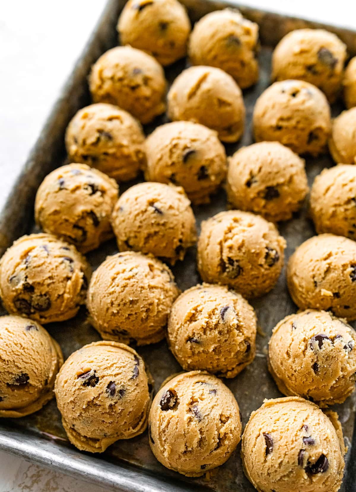 peanut butter chocolate chip cookie dough balls on baking sheet.