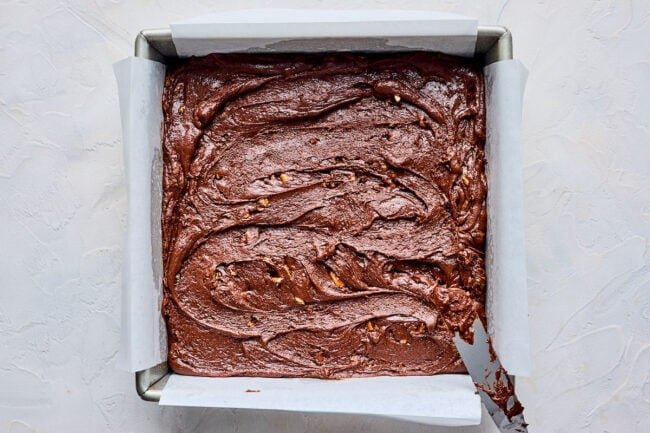 chocolate fudge spread in a baking pan with parchment paper. 