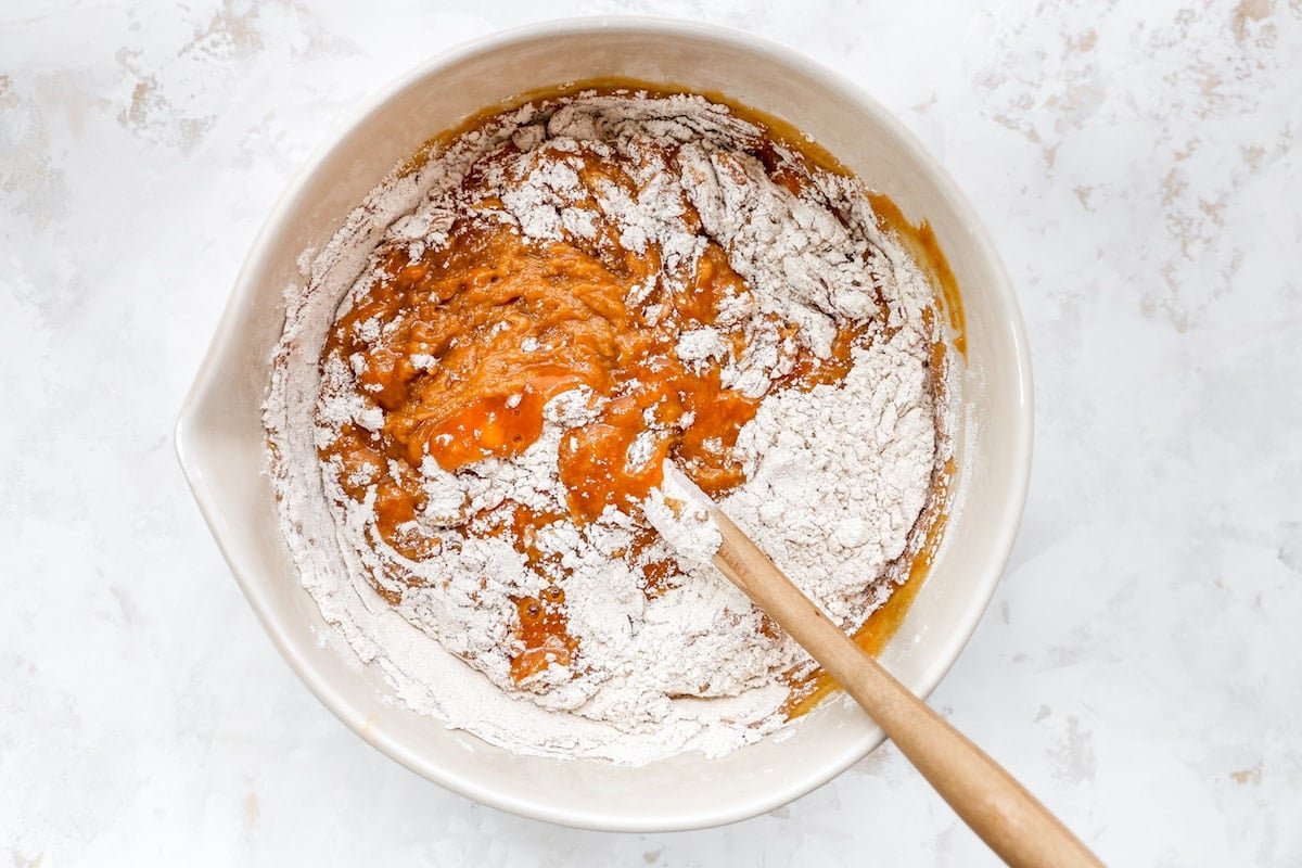 pumpkin bread batter being mixed with spatula in mixing bowl.