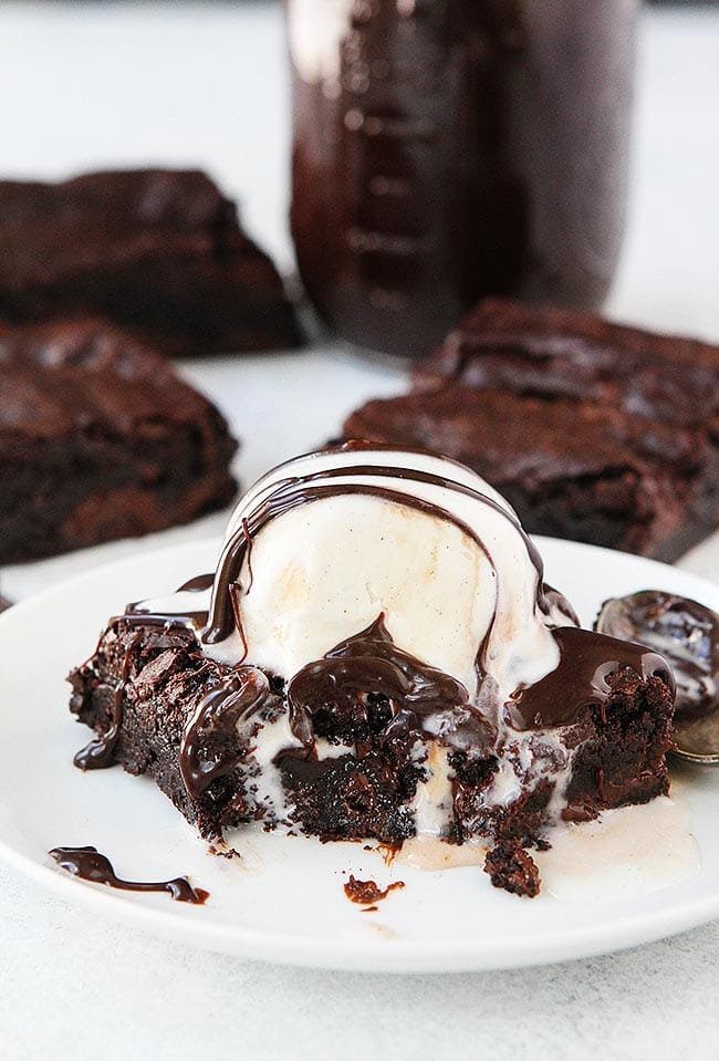 Fudgy brownie with ice cream and hot fudge on plate.