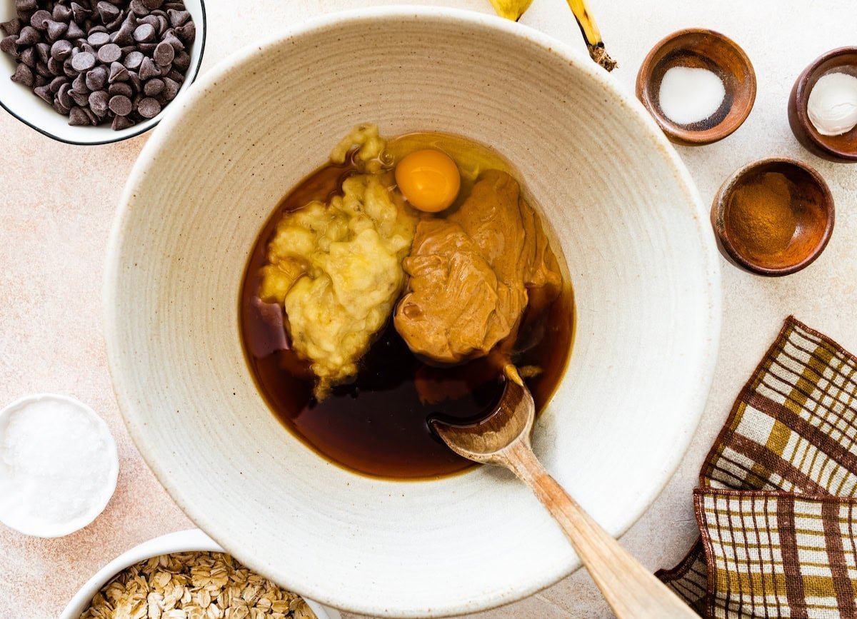 peanut butter, bananas, egg, maple syrup, and vanilla in mixing bowl with spoon. 