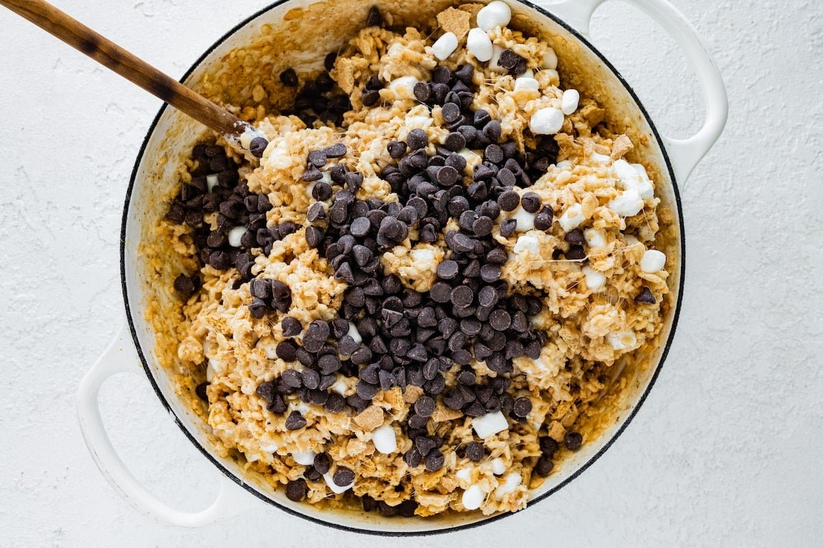 s'mores rice krispie treats with graham crackers and chocolate chips in pot with wooden spoon. 