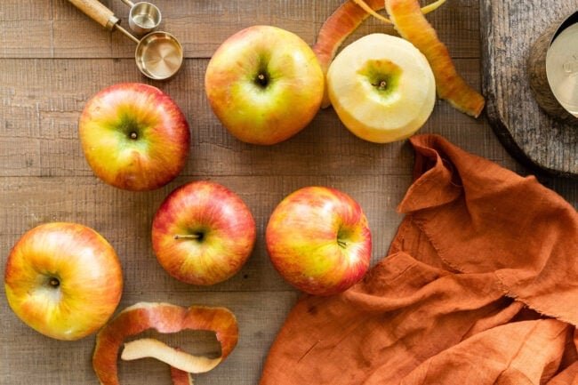 apples and peeled apples on cutting board.