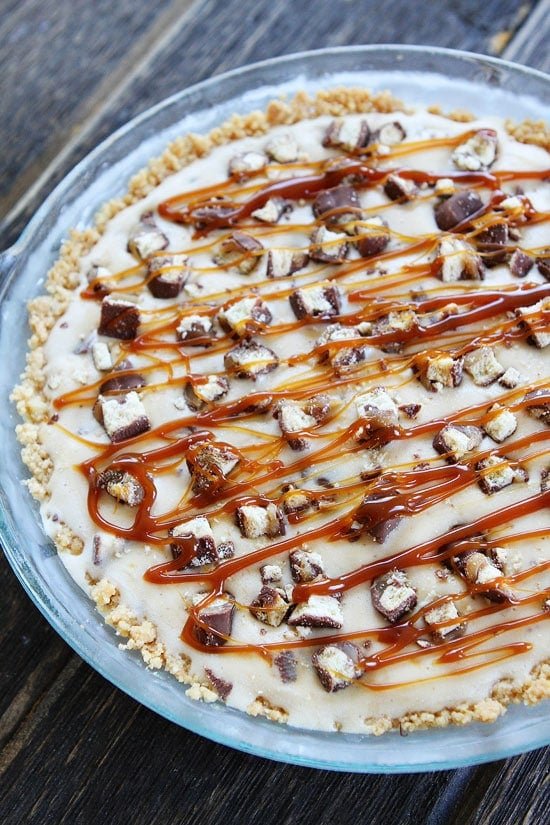 Twix Ice Cream Pie Recipe on twopeasandtheirpod.com Shortbread cookie crust with a layer of chocolate, vanilla ice cream, chopped Twix candy bars, and salted caramel sauce. This pie is the BEST summer dessert! Twix Ice Cream Pie in pie pan