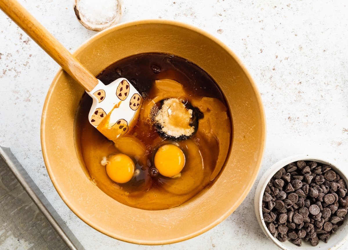 peanut butter, maple syrup, eggs, vanilla, baking powder, and baking soda in mixing bowl with spatula.