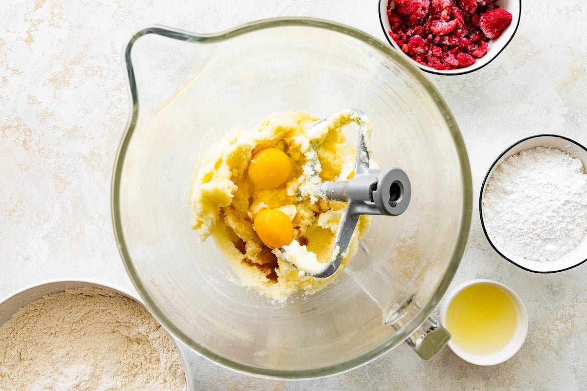 butter, sugar, eggs, and vanilla being mixed together with beater blade in mixing bowl.
