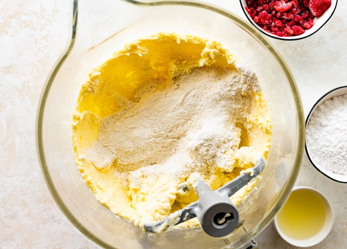 dry ingredients being added to butter mixture in mixing bowl.