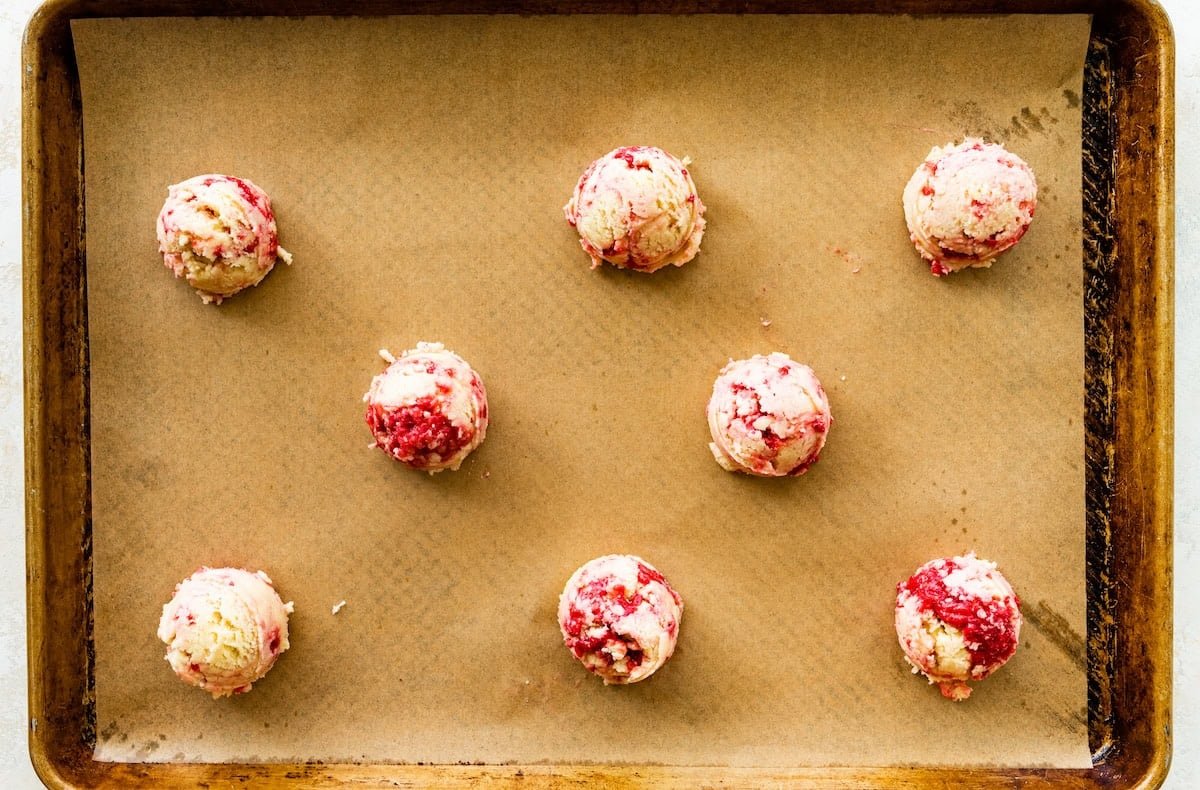 lemon raspberry cookie dough balls on baking sheet with parchment paper.