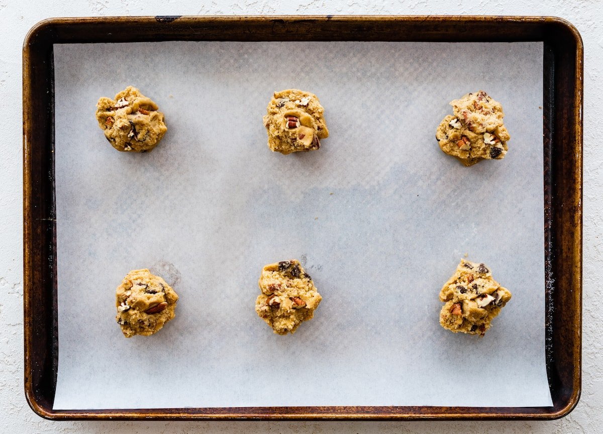 maple pecan chocolate chip cookie dough balls on baking sheet with parchment paper.