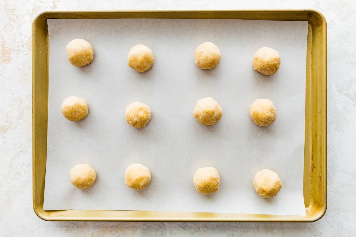 brown butter sugar cookie dough balls on baking sheet with parchment paper.