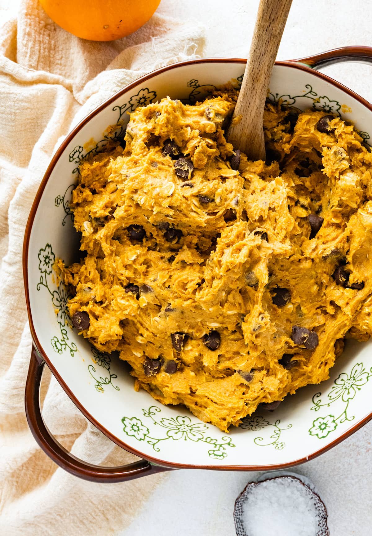 pumpkin oatmeal chocolate chip cookie dough in mixing bowl with wooden spoon.