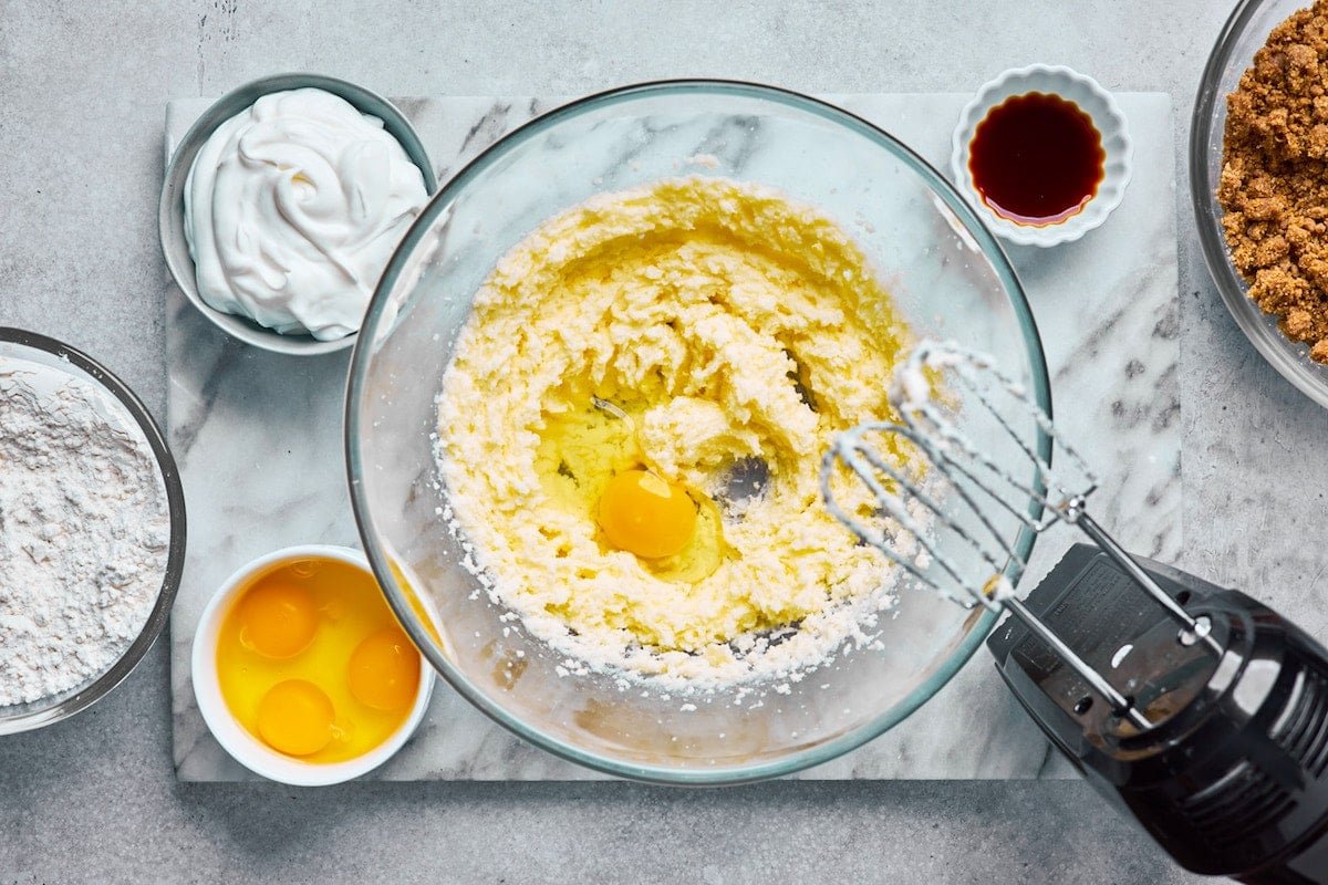 creaming butter and sugars together with mixer to make coffee cake and adding the eggs.