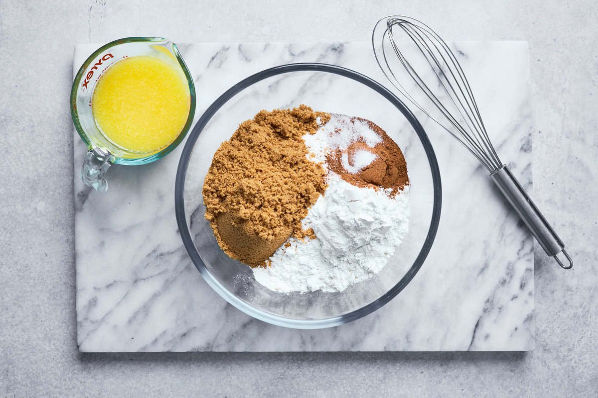 coffee cake dry ingredients in a bowl with whisk and melted butter in measuring cup.