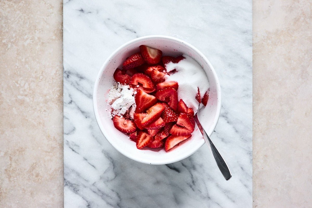 sliced strawberries in bowl with sugar and cornstarch.