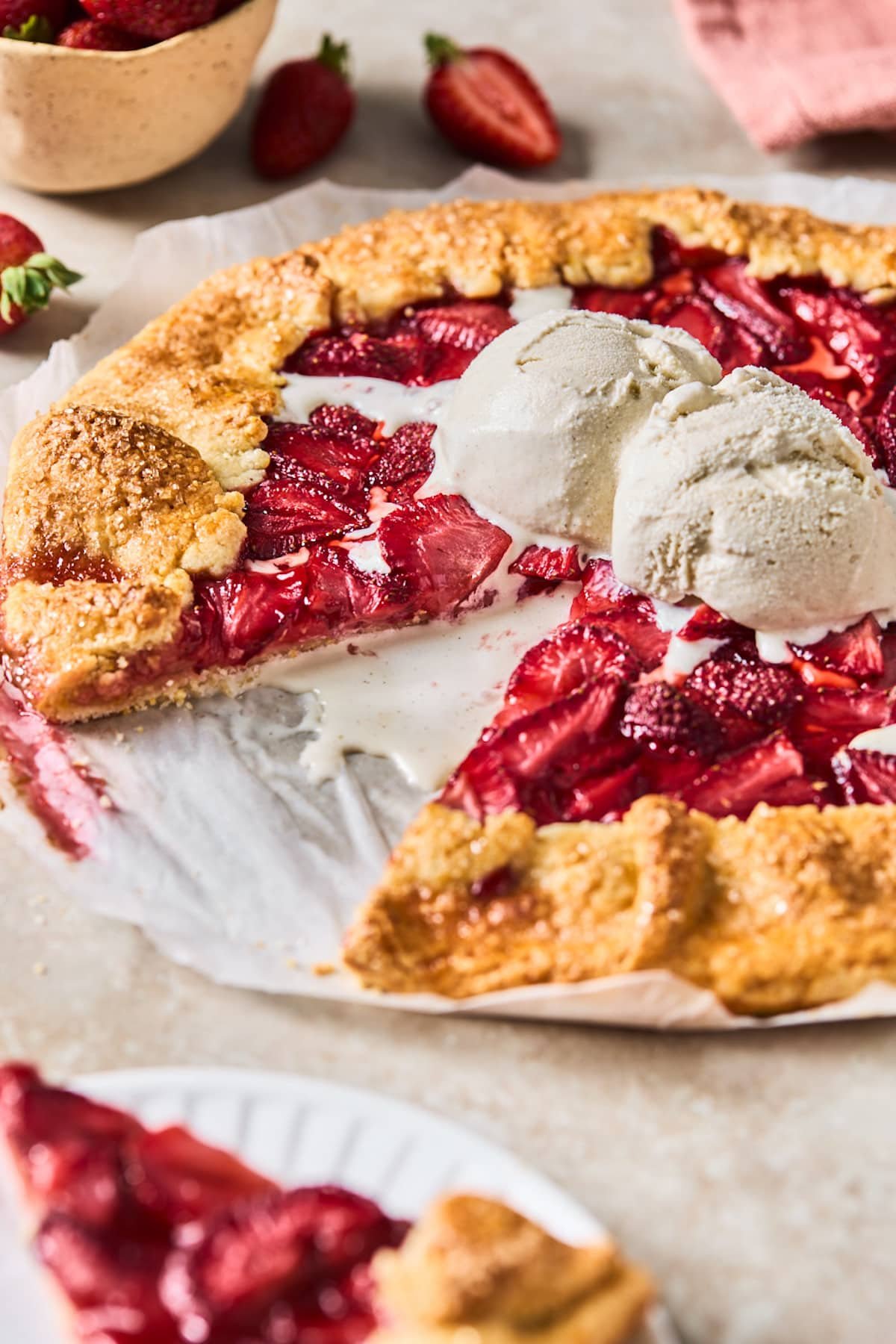 strawberry galette with a piece cut out and vanilla ice cream on top.