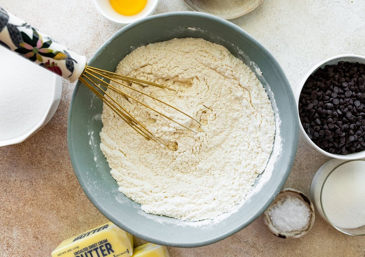 dry ingredients being whisked together in mixing bowl to make chocolate chip sugar cookies.