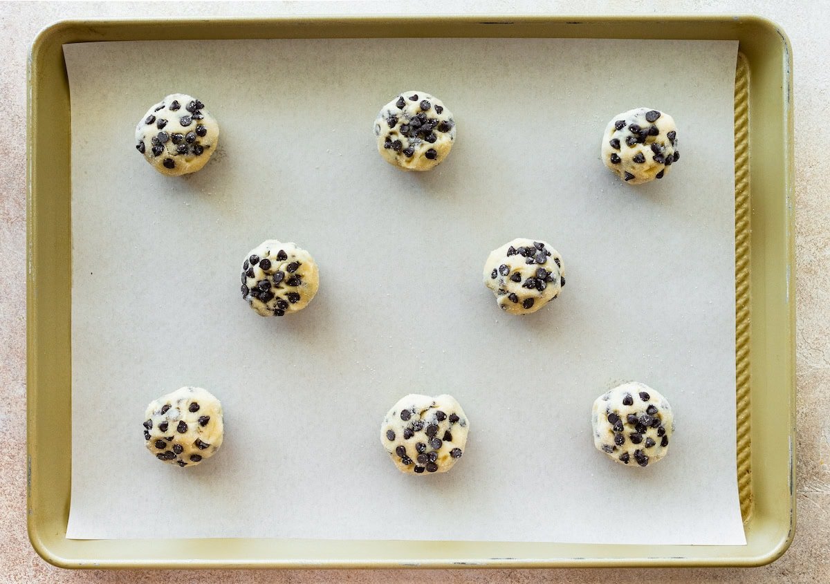 chocolate chip sugar cookie dough balls on baking sheet with parchment paper.