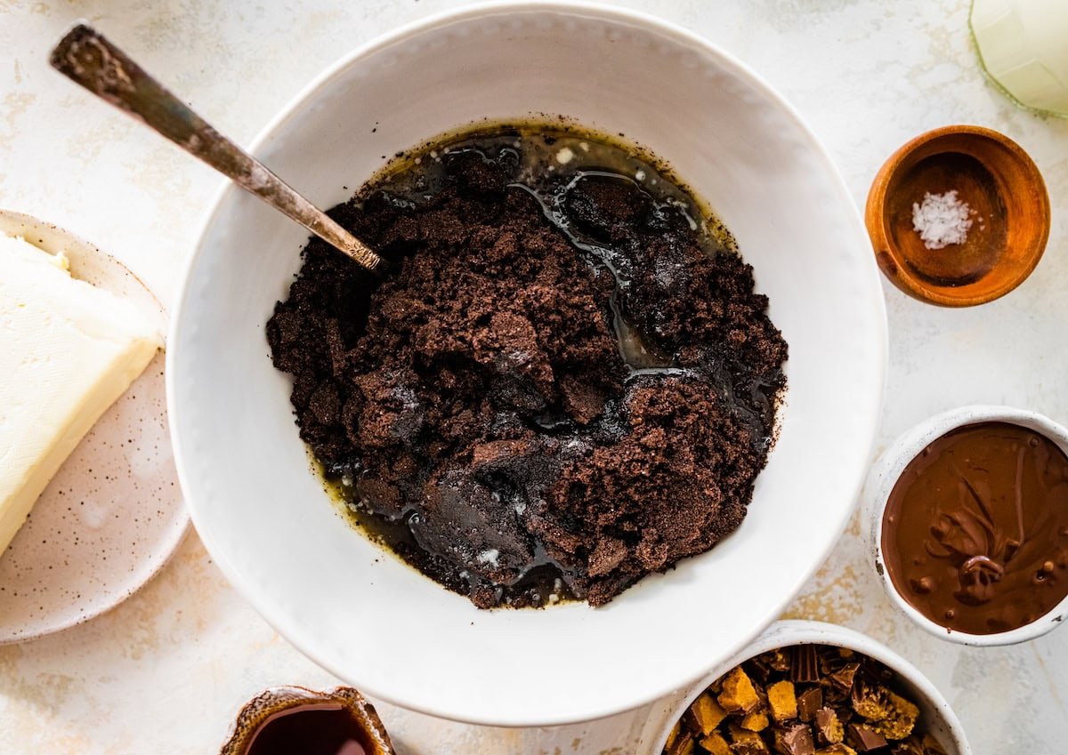 Oreos and melted butter in mixing bowl with spoon.