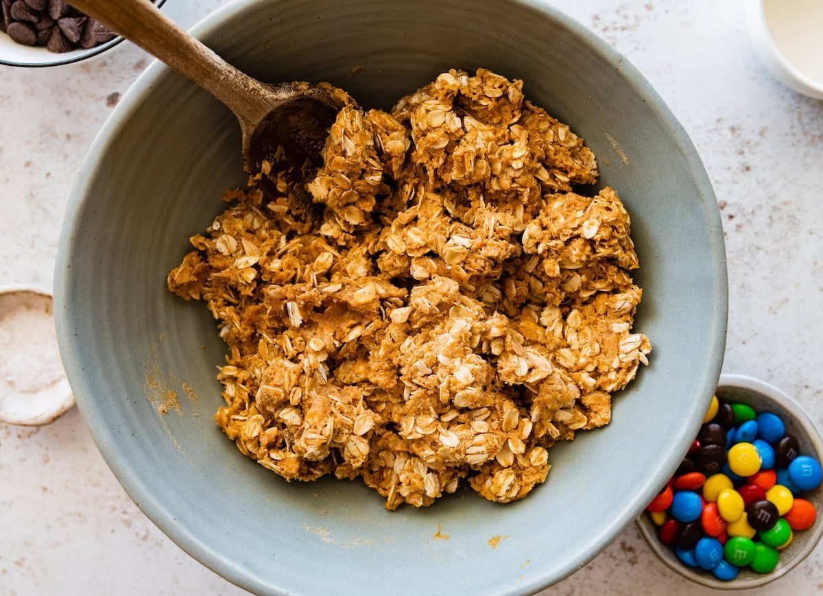 peanut butter oat mixture in mixing bowl with wooden spoon.