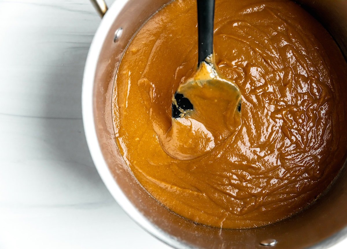 scotcheroo peanut butter corn syrup mixture in pan with spoon.