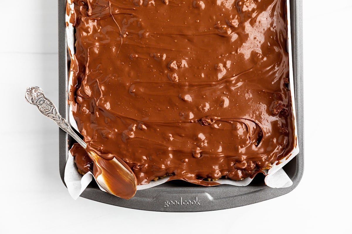 scotcheroos in pan with chocolate on spoon.