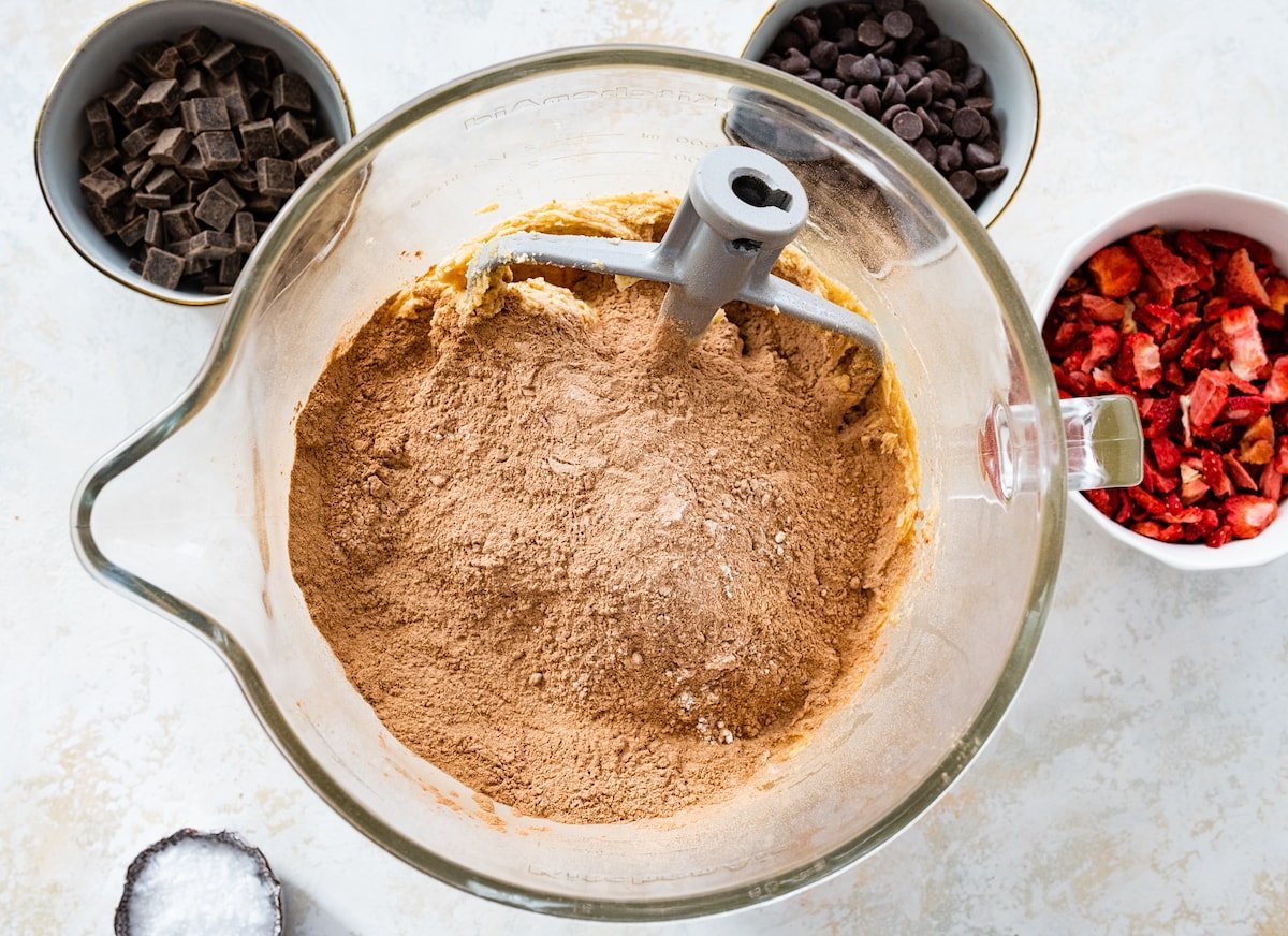 adding dry ingredients to butter mixture in mixing bowl.